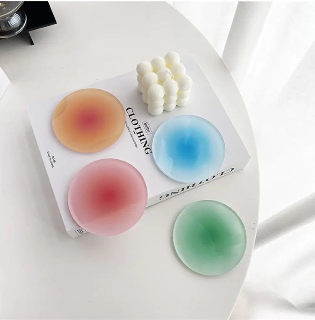 four, colors acrylic gradient coasters on a white coffee table
