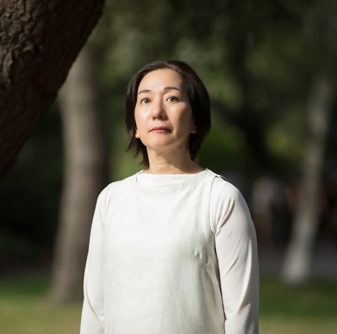 headshot of Chisato Minamimura  in a white shirt with trees in the background