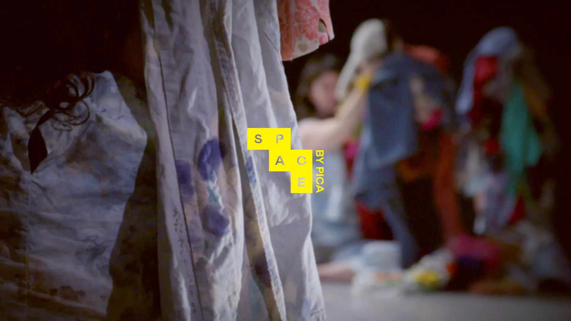 People in colorful outfits with the SPACE logo in yellow in the front. 