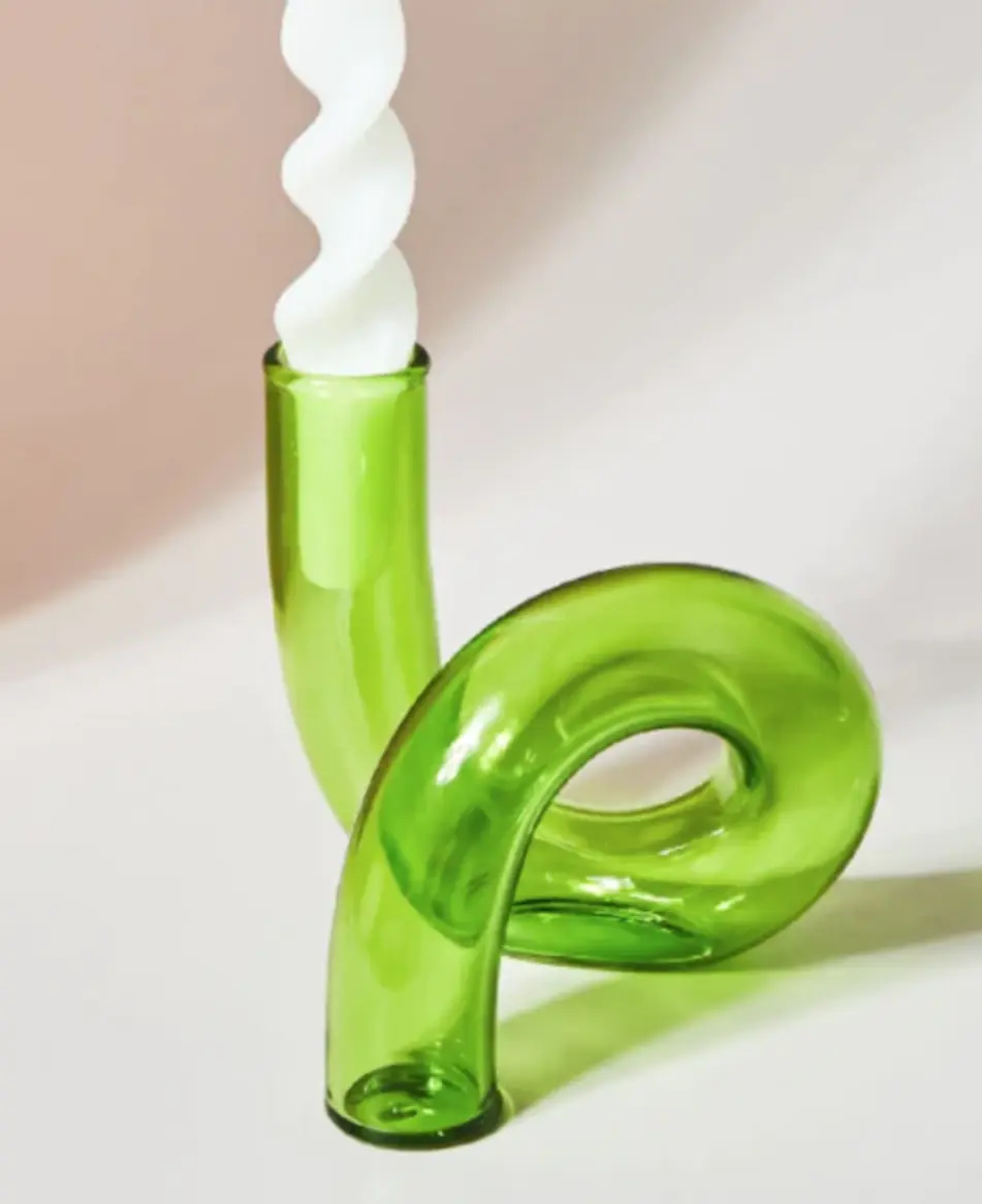 green loop-shaped glass vase with a white twisted taper candle in it