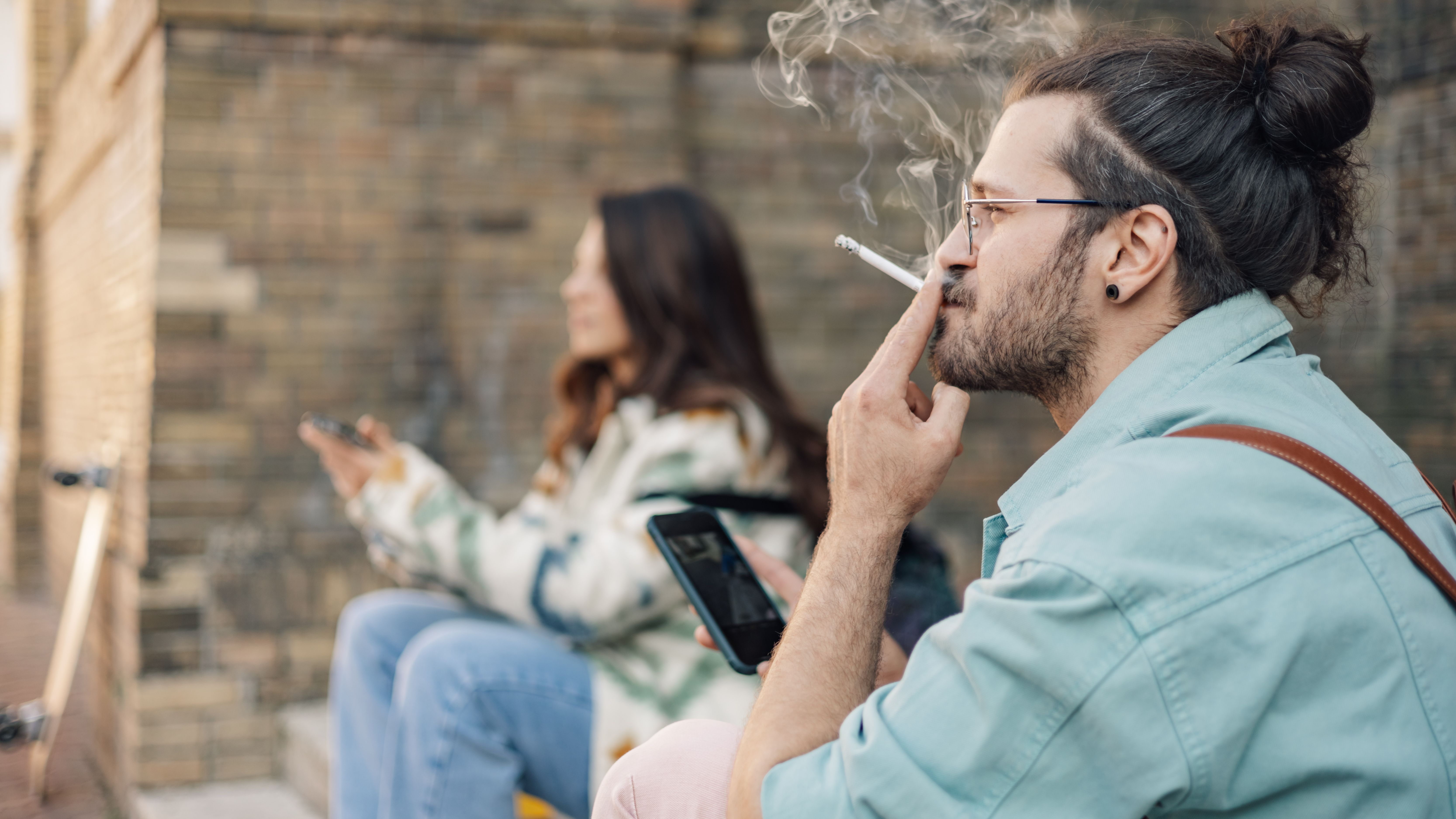 side-view-of-hipster-guy-using-cellphone-and-smoki-2025-04-03-19-46-12-utc.jpg