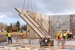 JB STEEL workers lifting concrete wall into place with a crane and chains
