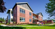 Metal and brick elementary school building with dark green lawn out front