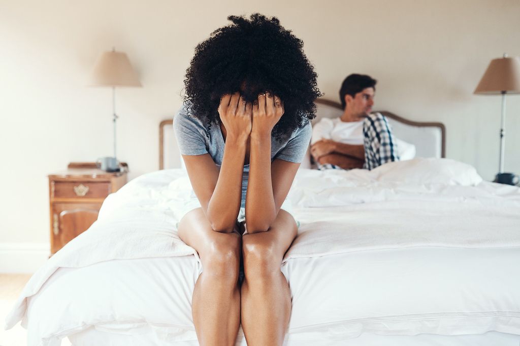 An upset woman on a bed with her boyfriend