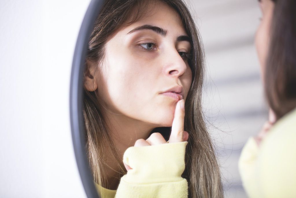 Woman examining a cold sore