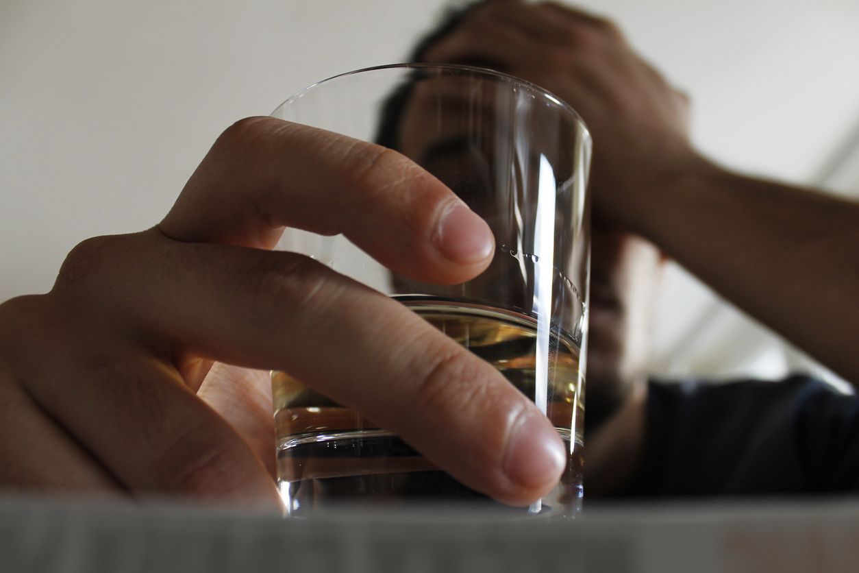 A stressed-out man holding a glass of alcohol