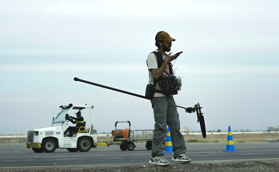 Crew member holding boom mic and walkie talkie