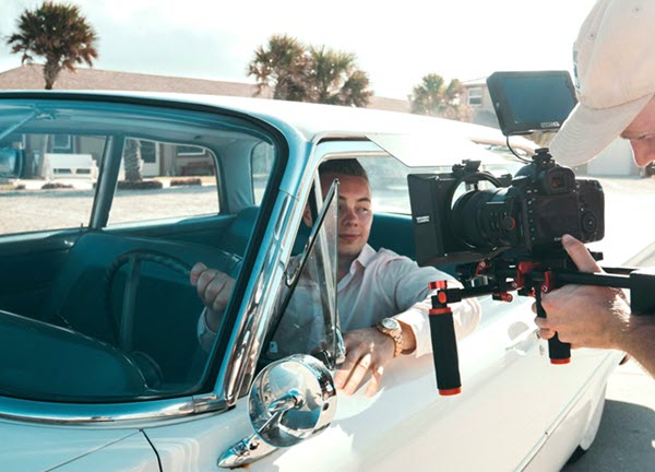 Person driving classic car being filmed through open window