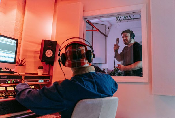 Recording engineer looking at singer in sound booth