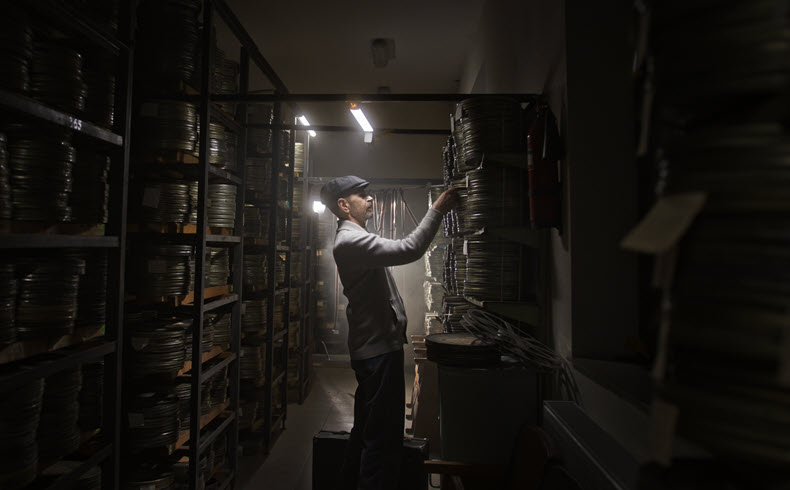 Film archivist or storage worker looking through stacks of film cans