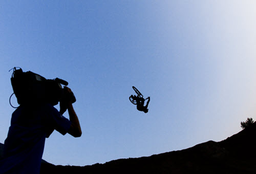 Silhouette of a camera operator filming a trick bicycle shot on location