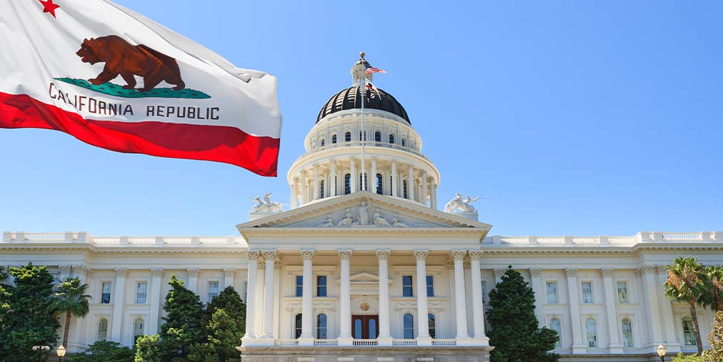 California state capital building with flag in the foreground