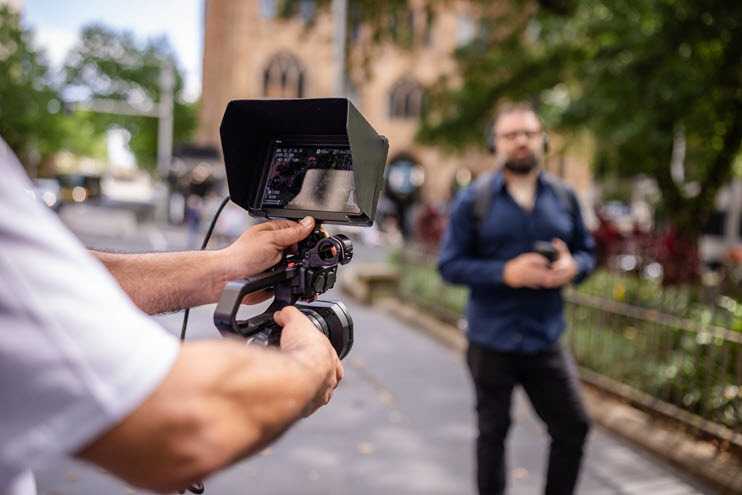 Camera person filming person walking down street