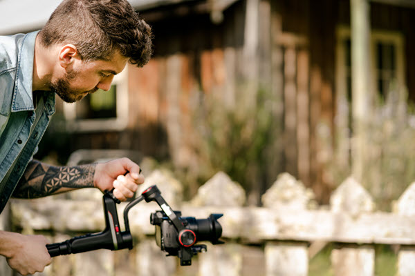 Camera man with tattoos holding camera on gimble