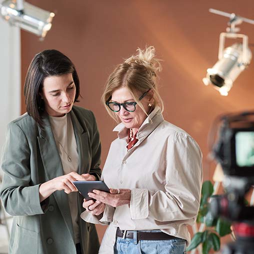 Two film production professionals review incentive updates on a tablet on set