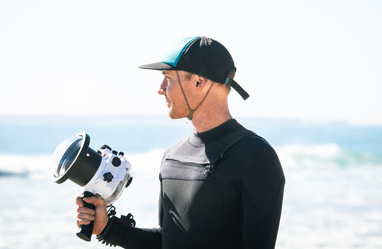 New Zealand filmmaker holding underwater camera at beach
