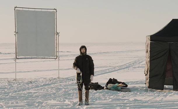 Production crew grip holding electrical cord on exterior snowy set