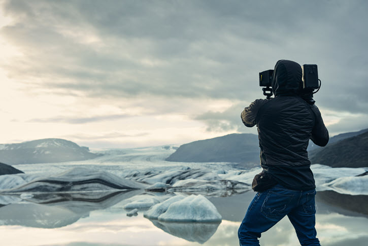 Camera operator filming remote glacial landscape