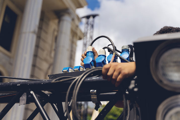 Lighting technician connecting cords to lighting rig