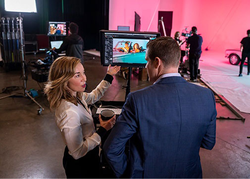 Producers discussing a take and movie production budgeting in front of a monitor on set