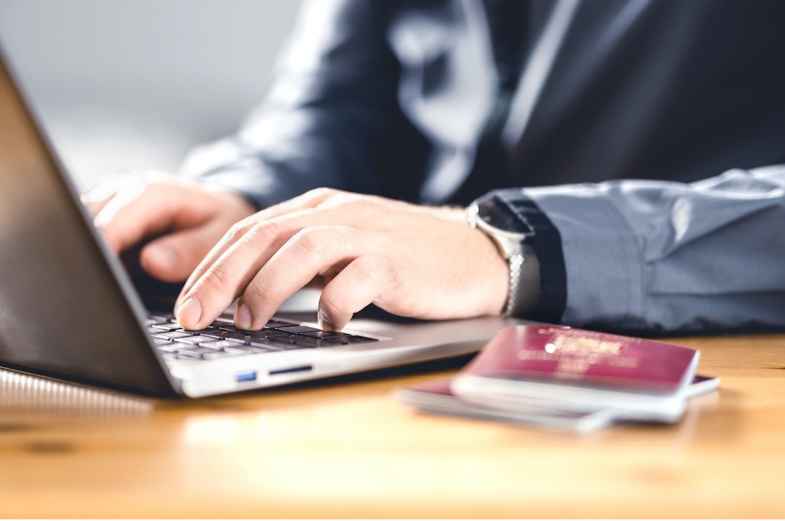 Man typing on laptop with passport nearby.jpg