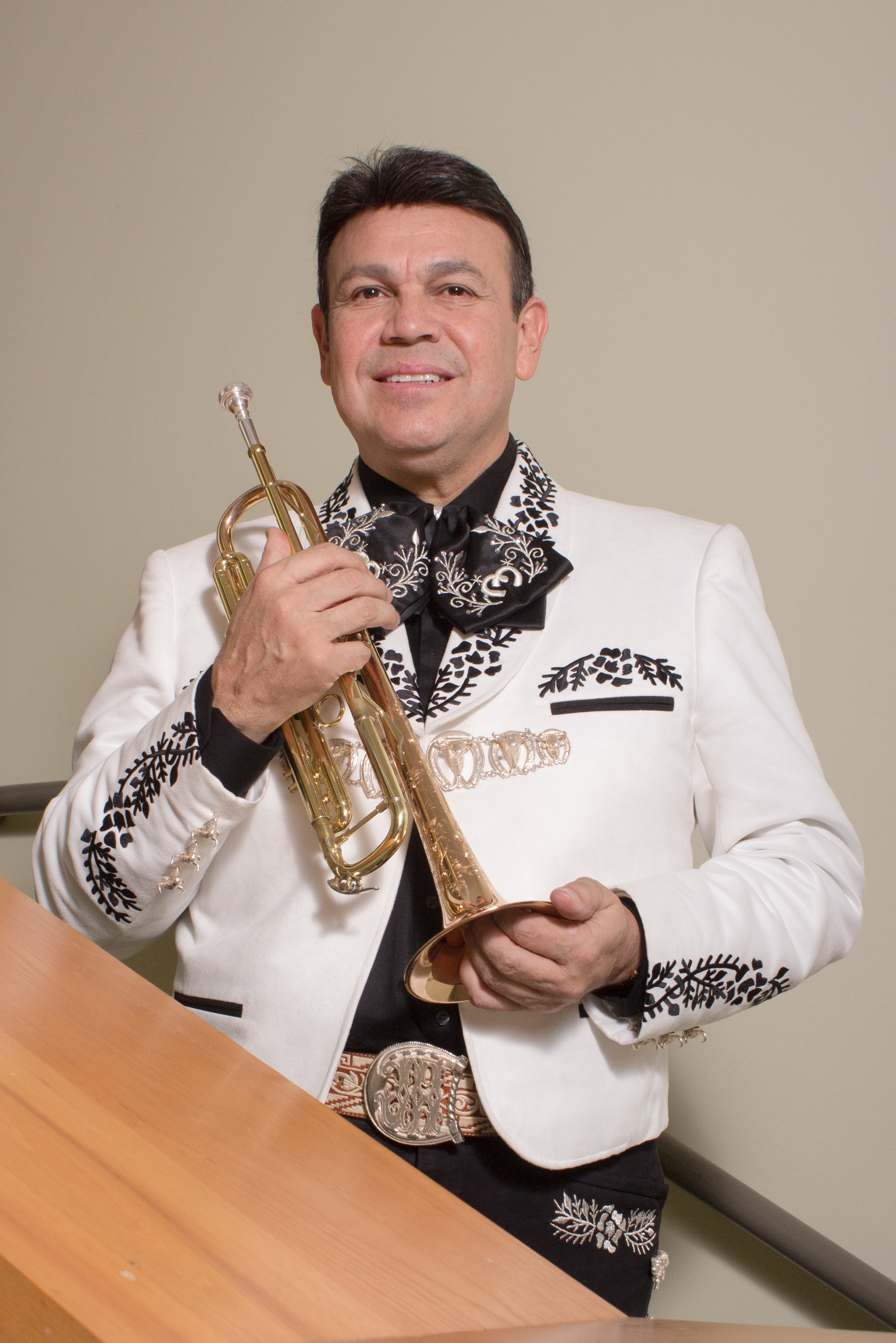 Jose Hernandez holding a trumpet in traditional Mariachi attire. 