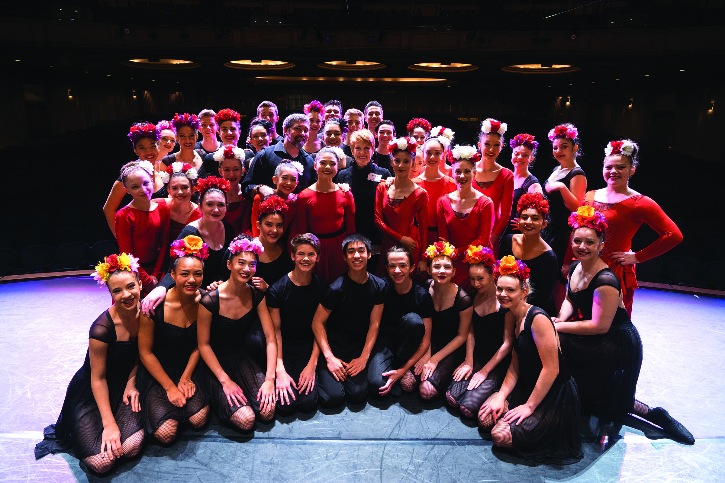 Dance West dancers and teachers posing on a stage. 