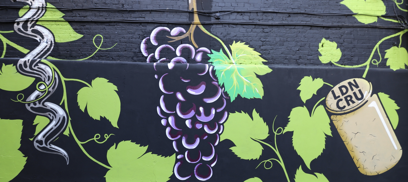 Photo of a wall painted with a grape vine and London Cru logo at London Cru