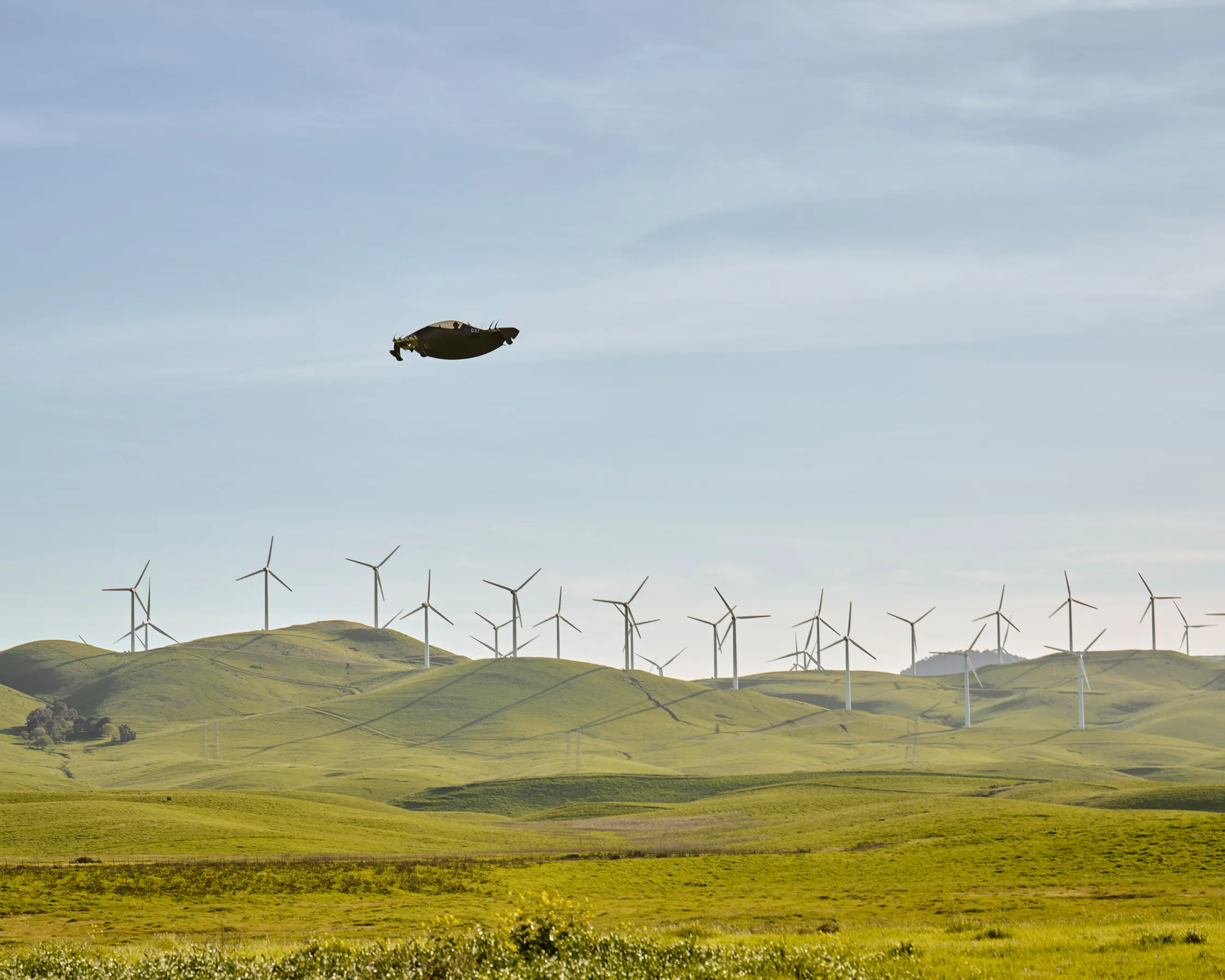 Pivotal BlackFly flying over countryside with wind turbines