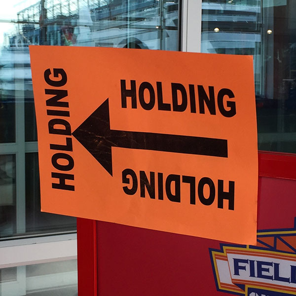 Orange sign with left pointing arrow and word holding