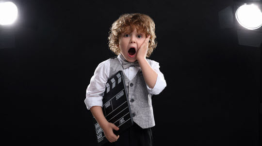 Child actor making shocked face holding clapboard