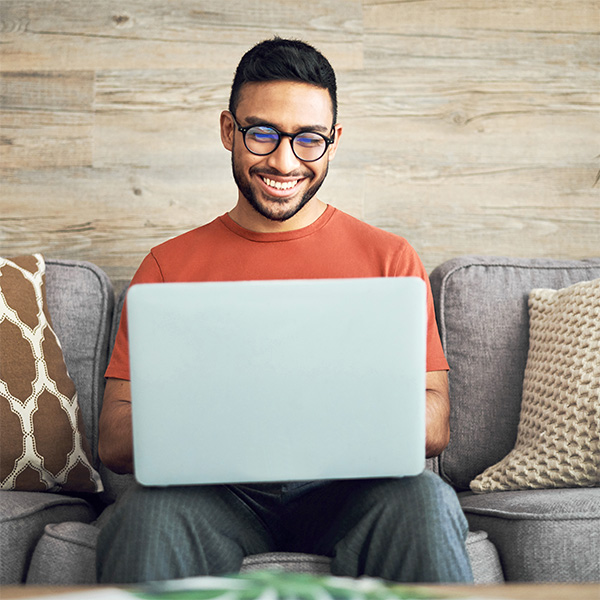 A smiling man looking at his laptop