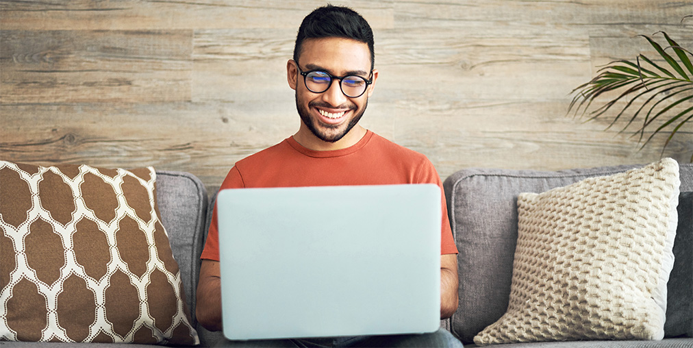 A smiling man looking at his laptop