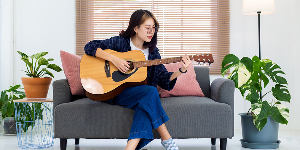 A woman on a couch playing guitar