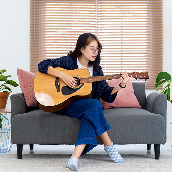 A woman on a couch playing guitar