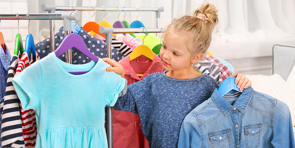 A girl holding two shirts