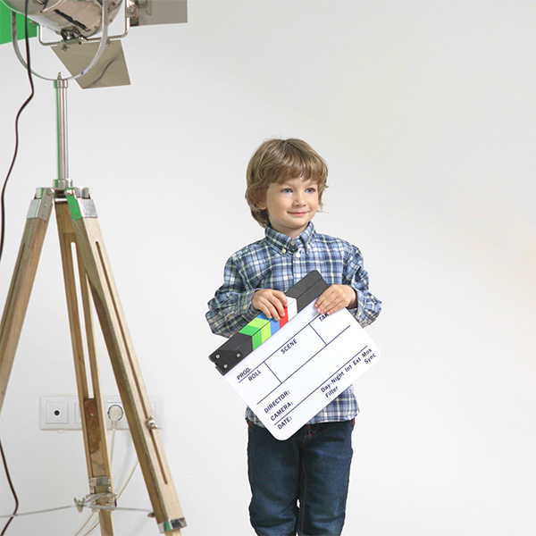 A young boy holding a clapperboard