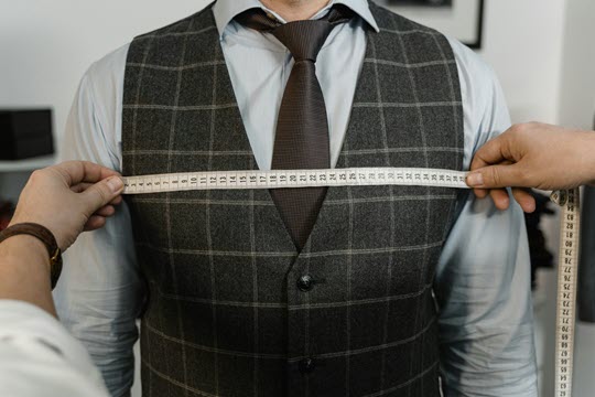 Person wearing vest and tie getting chest measured