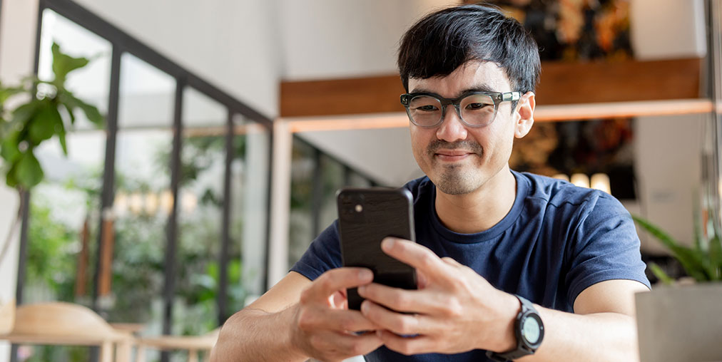 A smiling man looking at his phone.