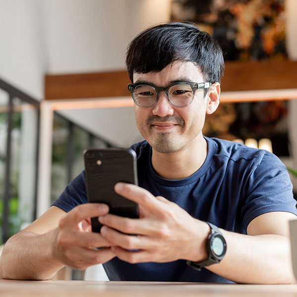 A smiling man looking at his phone.
