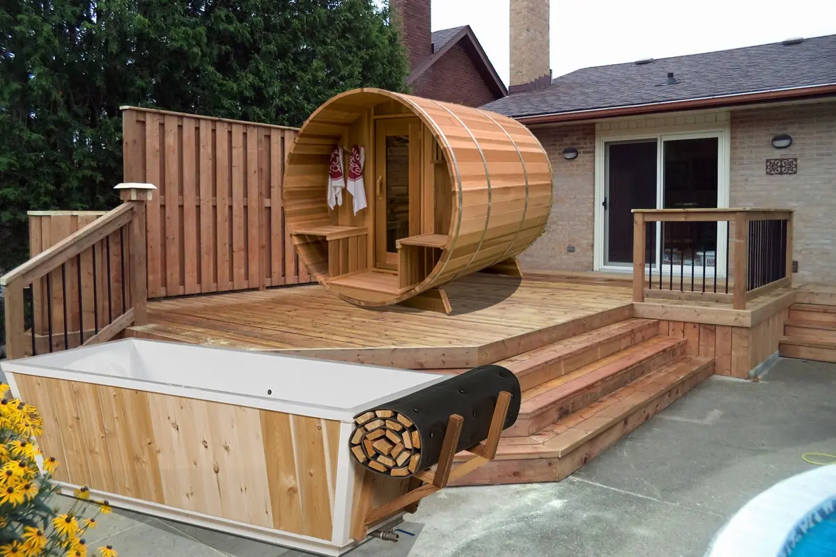 A cedar barrel sauna and a cold plunge set up together on a backyard deck