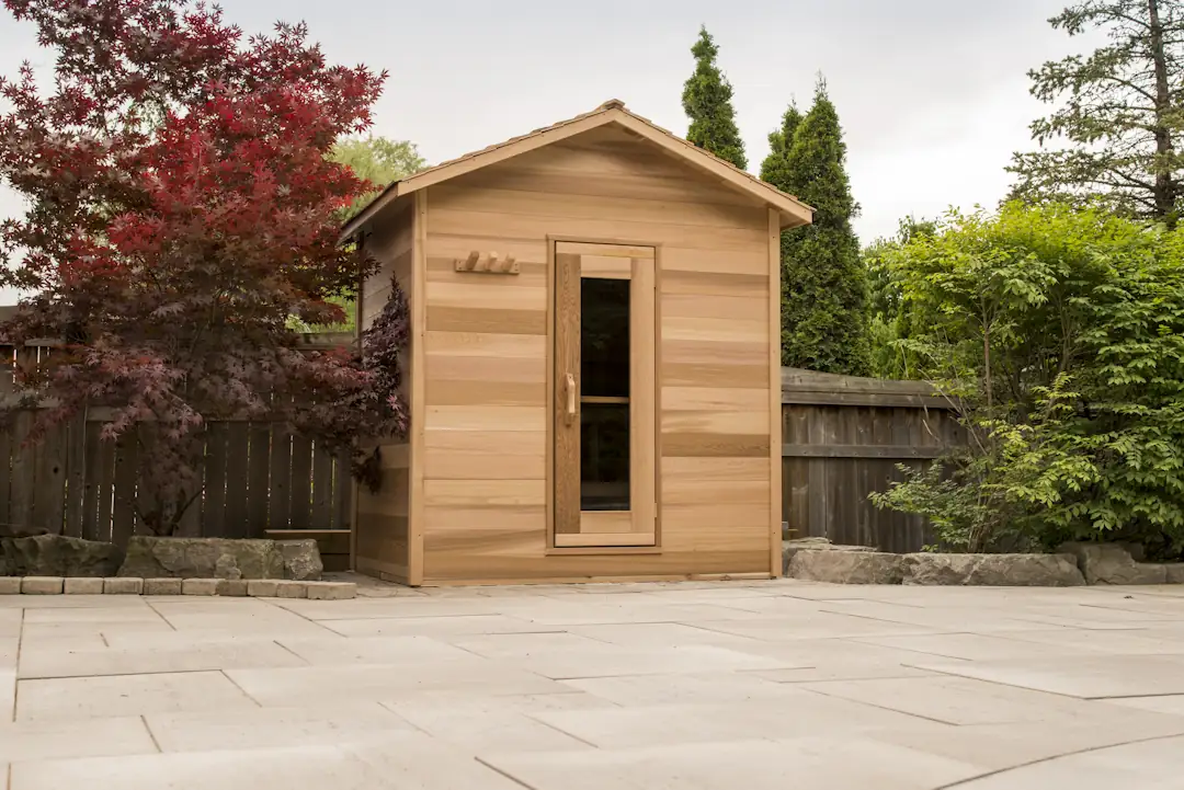 LeisureCraft cabin sauna with cedar shingle roof on a backyard patio
