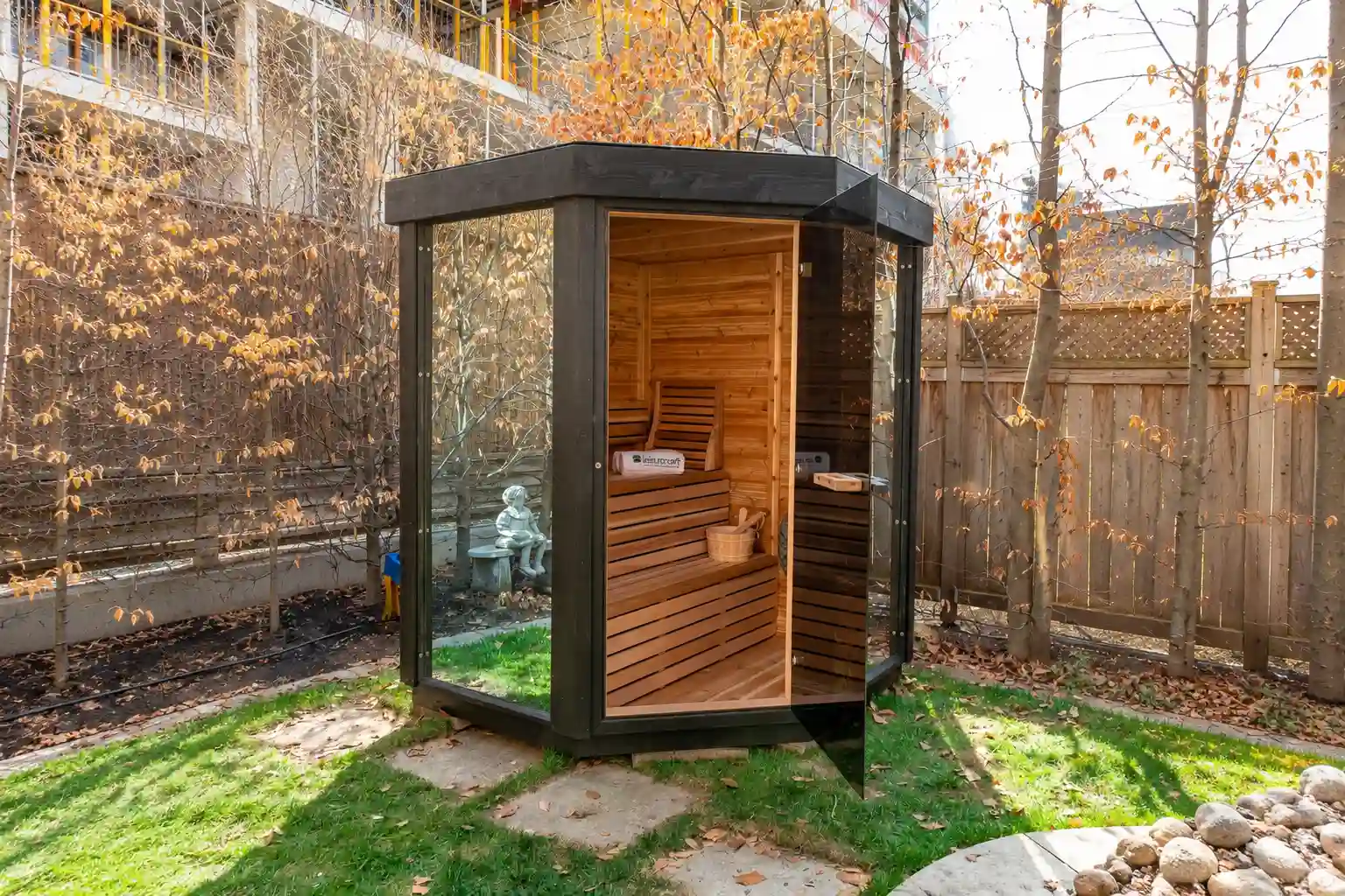 LeisureCraft Pure Cube Trinity corner sauna in a backyard, its dark-stained exterior frame and Western Red Cedar interior finished with Livos oil