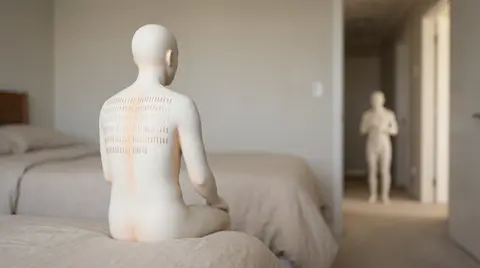 Una figura de porcelana sin rostro sentada de espaldas, con decenas de costuras doradas pequeñas e idénticas en los hombros, mientras otra figura pasa sin darse cuenta al fondo, que ilustra cómo el resentimiento en el matrimonio se acumula por cosas pequeñas que nadie menciona.