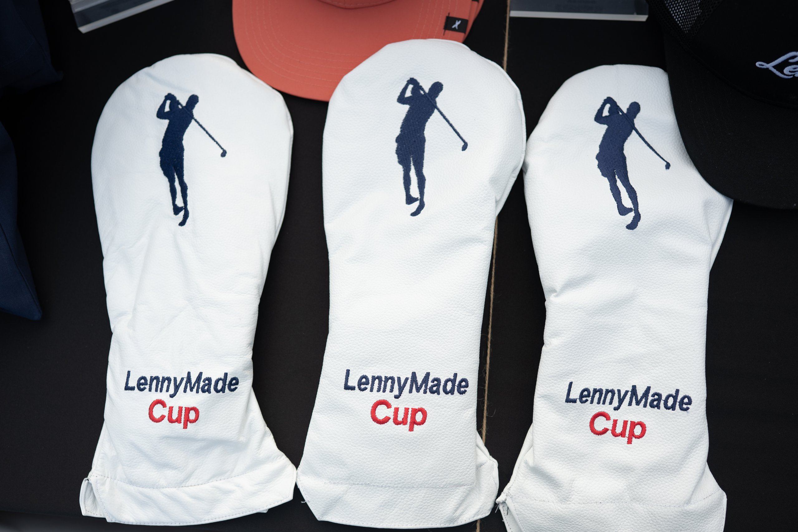 Three white leather LennyMade Cup driver headcovers with a navy golfer silhouette and red Cup lettering.