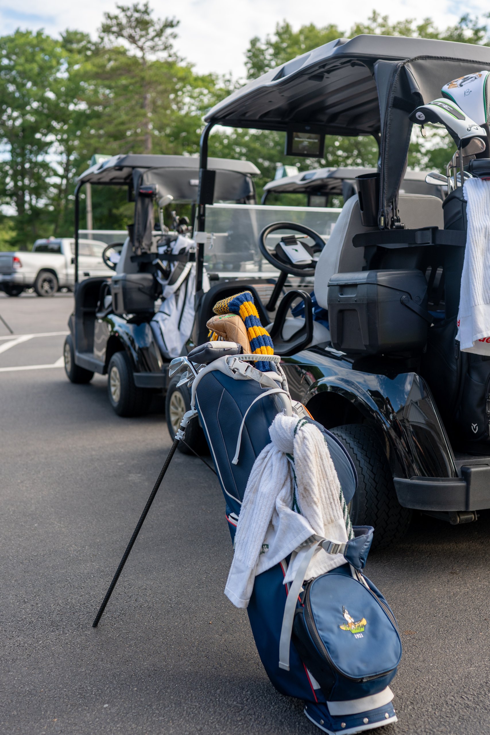 Golf bags loaded onto the backs of carts in the lot, towels and club headcovers ready for the round.
