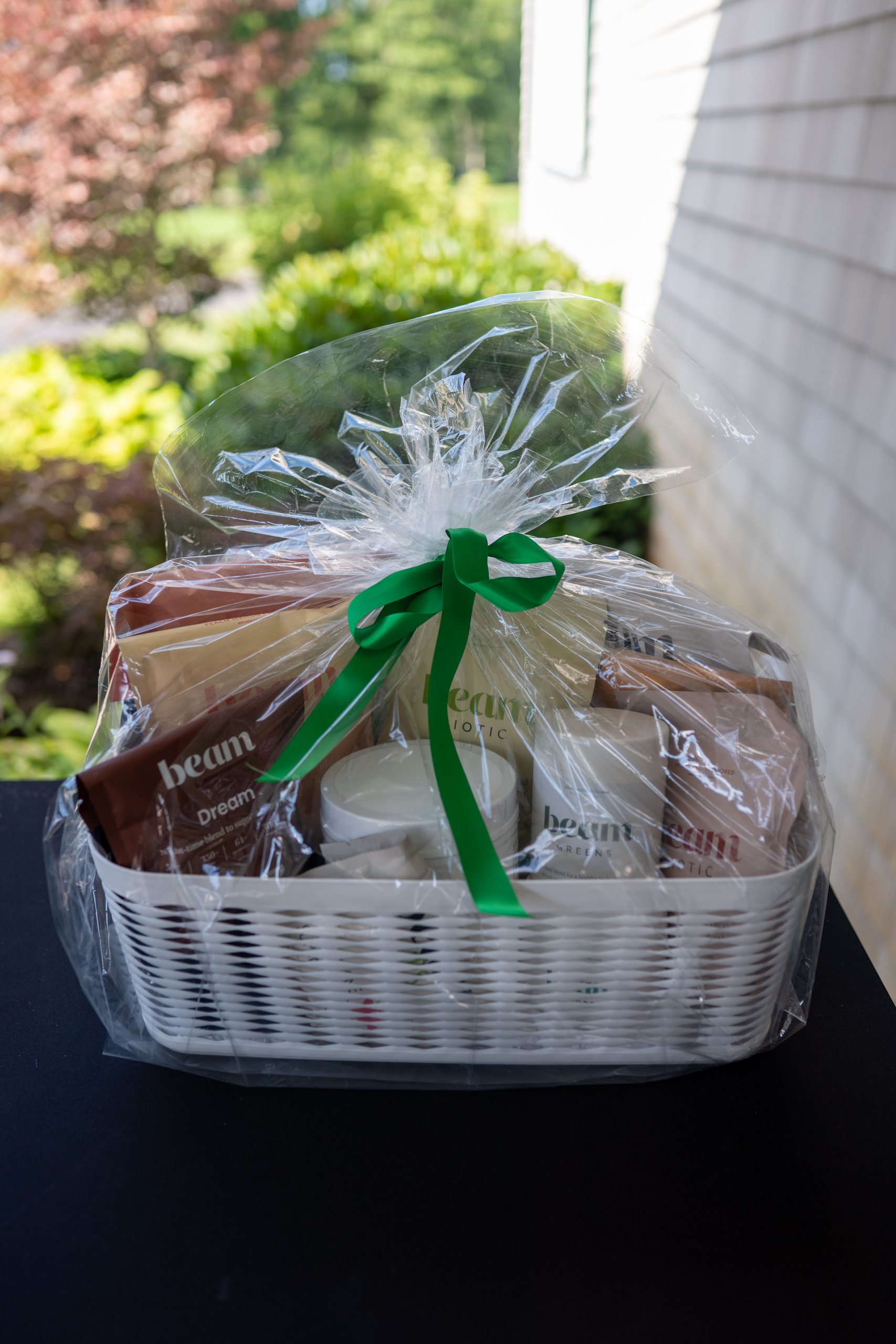 A cellophane-wrapped raffle basket of Beam wellness products tied with a green bow on the clubhouse porch.