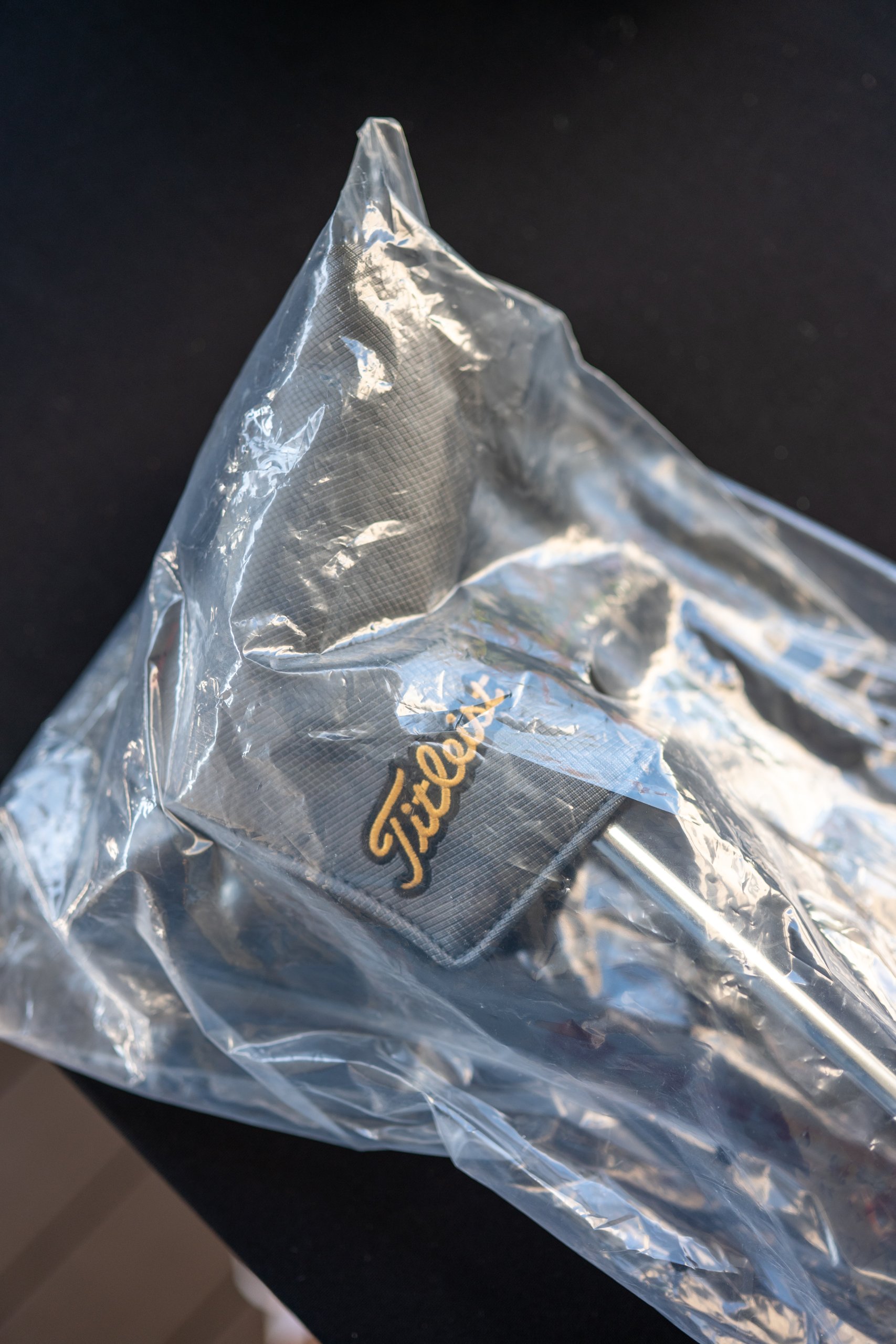 A Titleist golf item sealed in a clear bag on a black table as a raffle prize.