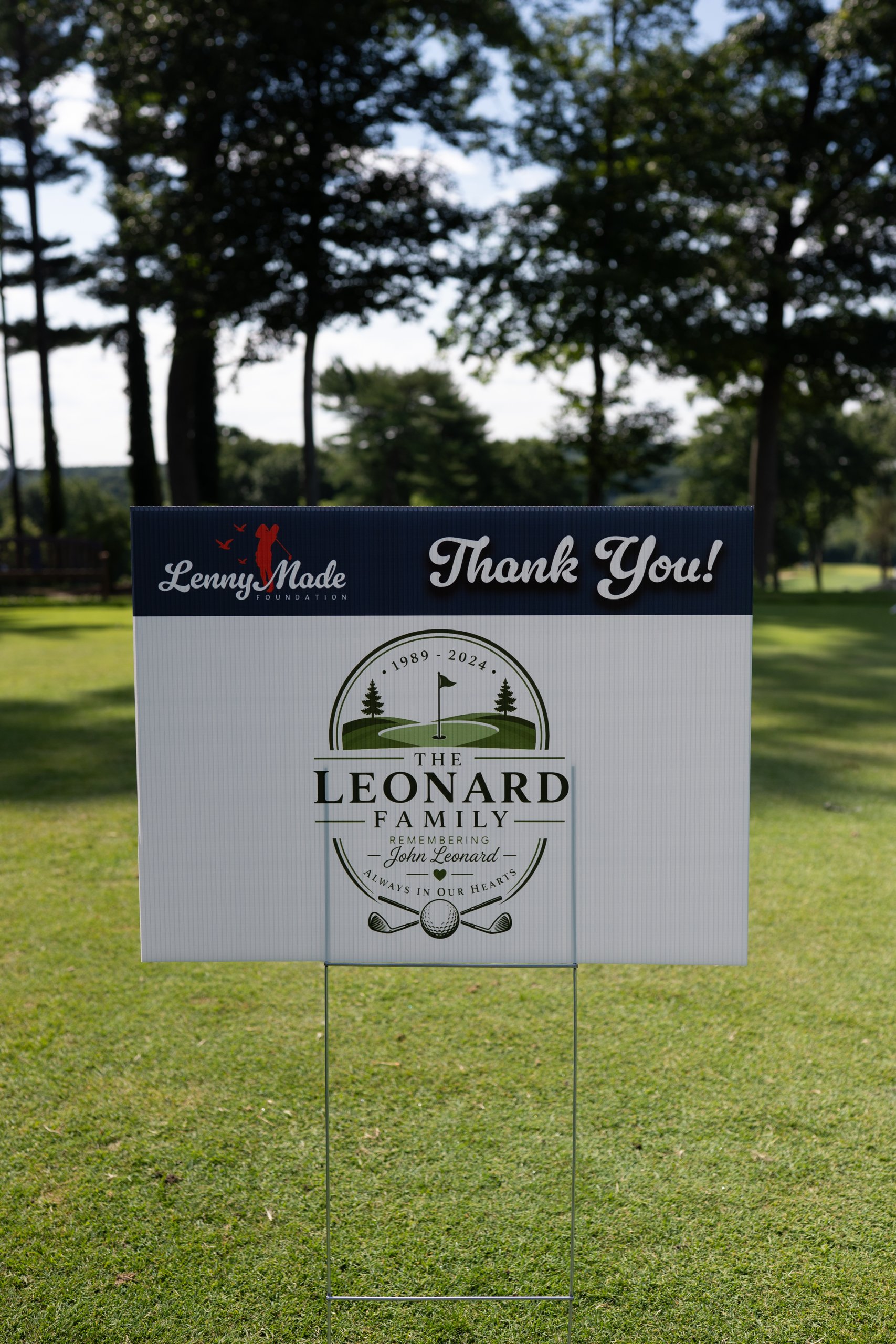 A LennyMade Foundation Thank You sponsor sign for the Leonard Family, remembering John Leonard, staked on the course.