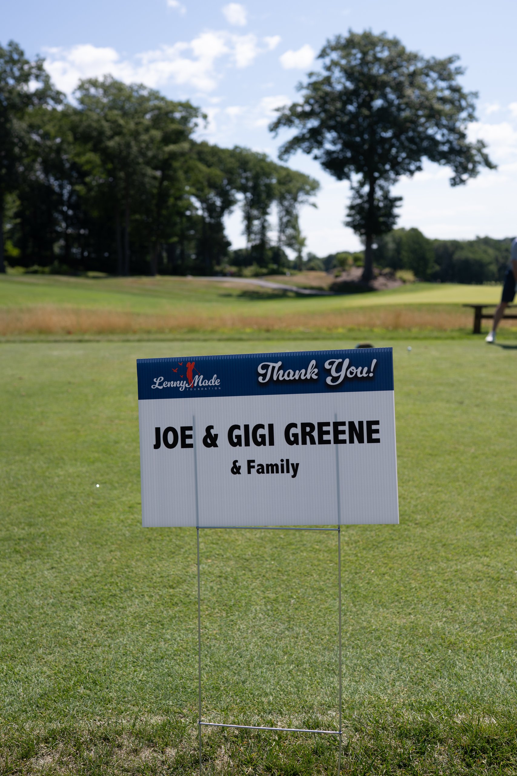 A LennyMade Foundation Thank You sponsor sign for Joe and Gigi Greene and Family staked on the tee.